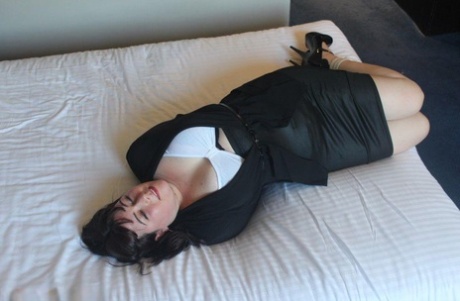 Dark haired lady shows her brassiere while bound and gagged on a bed 87087981